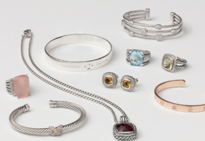 Collection of luxury designer jewelry from the premier luxury jewelry buyer in West Palm Beach, featuring Tiffany & Co. and Cartier bracelets, gemstone rings, cable-inspired cuffs, and pendant necklaces in silver and gold.